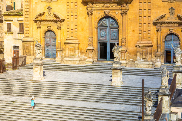 Young woman climbing the stairs of St Peter church, Modica, Ragusa province, Sicily, Italy