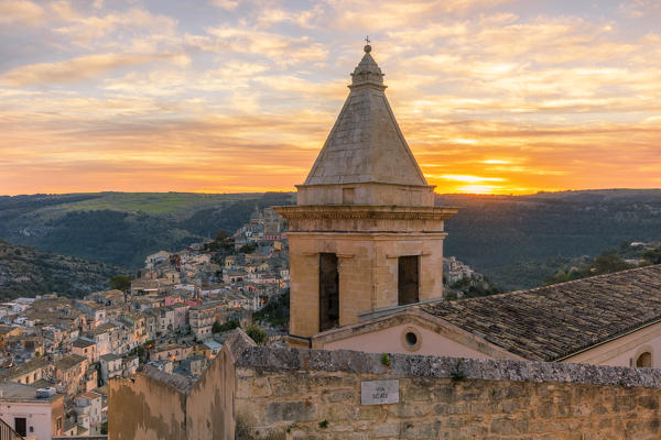 Close up of the bell tower of Santa Maria delle scale church and Ragusa Ibla in the background at sunrise, Ragusa, Sicily, Italy