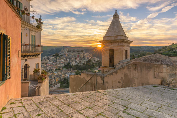Close up of the bell tower of Santa Maria delle scale church and Ragusa Ibla in the background at sunrise, Ragusa, Sicily, Italy