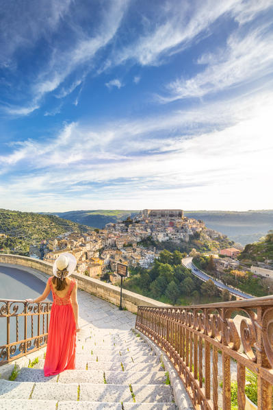 Young woman admiring the enchanting hilltop city of Ragusa Ibla from the stairs of Santa maria delle Scale church, Ragusa, Sicily, Italy  (MR)