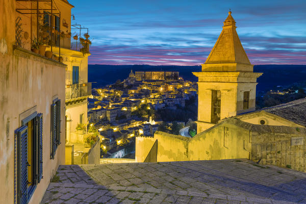 Close up of the bell tower of Santa Maria delle scale church and Ragusa Ibla in the background at sunrise, Ragusa, Sicily, Italy