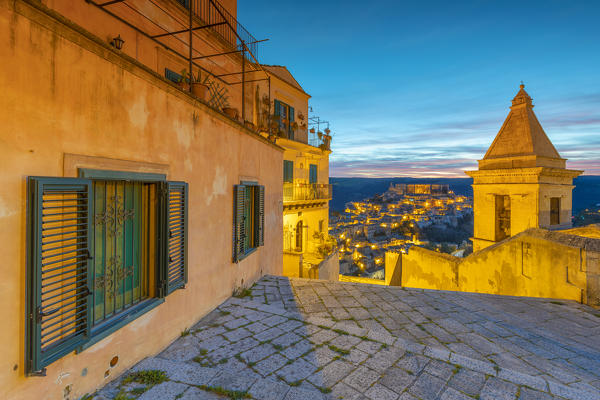 Elevated view of the bell tower of Santa Maria delle scale church and Ragusa Ibla in the background at sunrise, Ragusa, Sicily, Italy