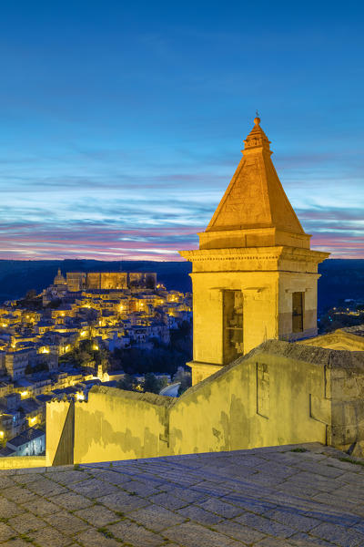 Close up of the bell tower of Santa Maria delle scale church and Ragusa Ibla in the background at sunrise, Ragusa, Sicily, Italy