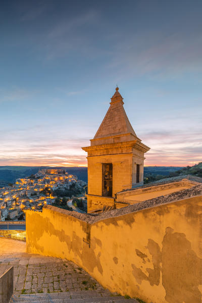 Close up of the bell tower of Santa Maria delle scale church and Ragusa Ibla in the background at sunrise, Ragusa, Sicily, Italy