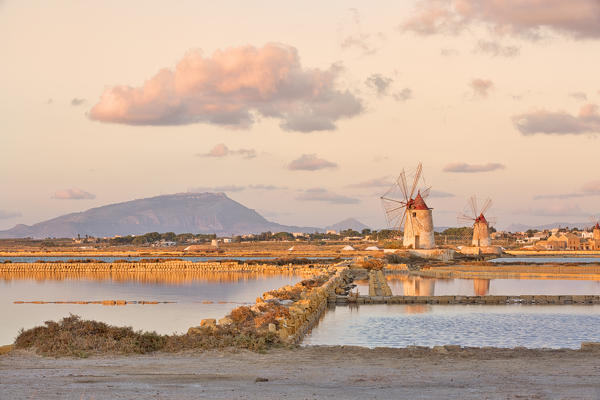 Salt pans with rows of tanks and two fully functional windmills on the coast connecting Marsala to Trapani, Trapani province,Sicily,Italy