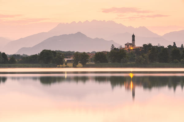 San Giuseppe Church and Bosisio Parini lakefront reflected in the Pusiano lake with Resegone mount in the background, Lecco province, Lombardy, italy