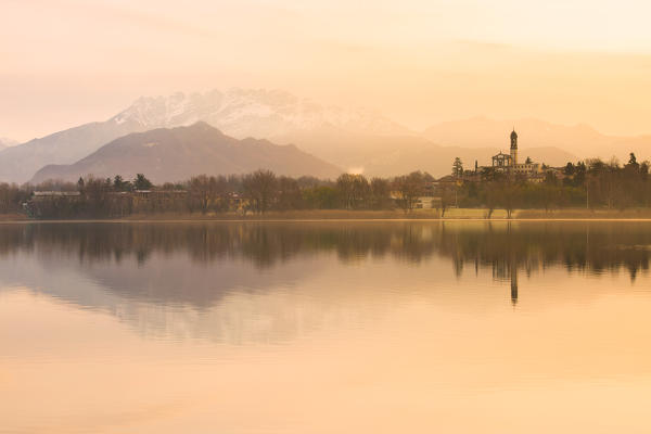 San Giuseppe Church and Bosisio Parini lakefront reflected in the Pusiano lake at sunrise, Lecco province, Lombardy, italy
