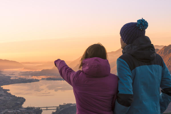 Hikers admiring Lecco and Adda river from San martino mount at dawn, Lecco, Lecco province, Lombardy, italy