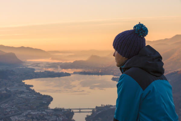 Hiker admiring Lecco and Adda river from San martino mount at dawn, Lecco, Lecco province, Lombardy, italy
