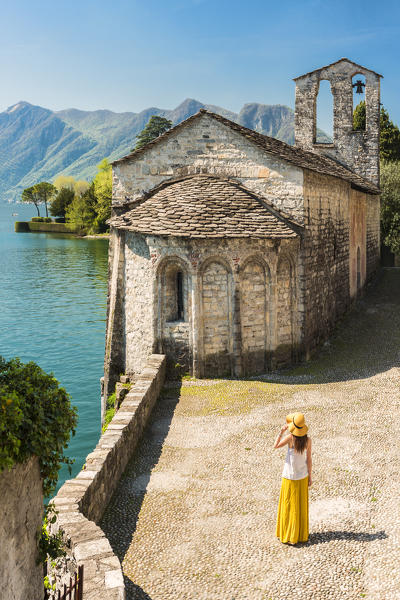 Young woman admiring San Giacomo church in Spurano, Ossuccio, Como province, Lombardy, italy (MR)