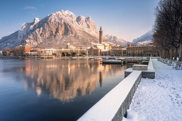 Snowy lakefront of Lecco and San Martino Mountain reflected in Como lake, Lecco province, Lombardy, Italy