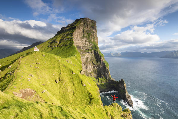 Hiker above the ocean towards Kallur lighthouse, Kalsoy island, Faroe Islands, Denmark