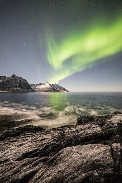 Frozen sea and rocky peaks illuminated by Northern Lights, Tungeneset, Senja, Tromso, Norway, Europe