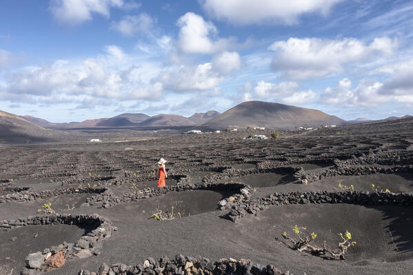 Girl with red dress walks in vineyards of Geria,Lanzarote, Canary Island, Spain, Europe