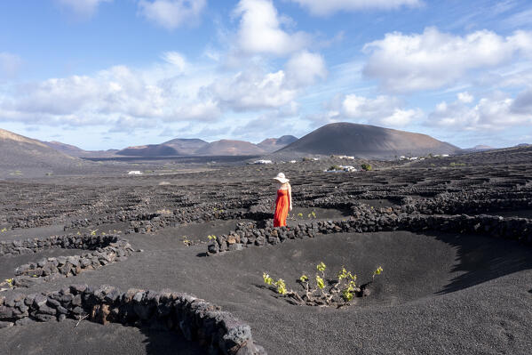 Girl with red dress walks in vineyards of Geria,Lanzarote, Canary Island, Spain, Europe