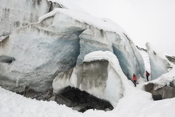 Couple of hikers near the ice cave of Morteratsch glacier,Morteratsch, Engadine, canton of Graubunden, Switzerland