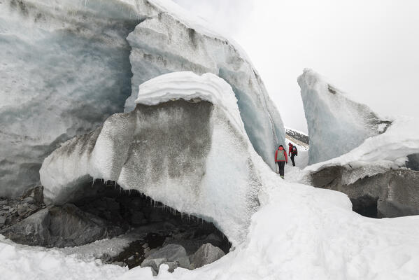 Couple of hikers outside of the ice cave of Morteratsch glacier,Morteratsch, Engadine, canton of Graubunden, Switzerland