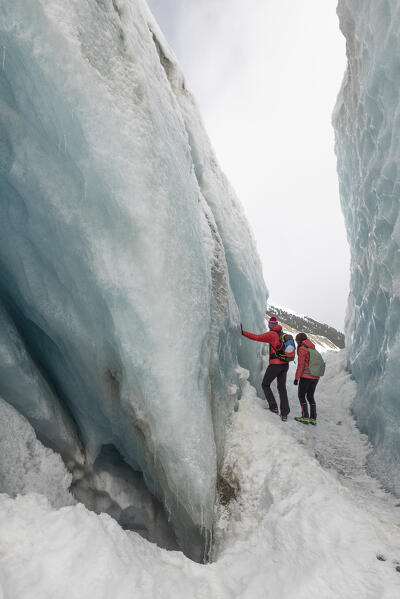 Couple of hikers admire the beauty of the ice of Morteratsch glacier,Morteratsch, Engadine, canton of Graubunden, Switzerland