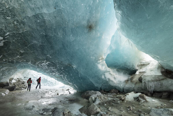 Couple of hikers inside ice cave of Morteratsch glacier,Morteratsch, Engadine, canton of Graubunden, Switzerland (MR)