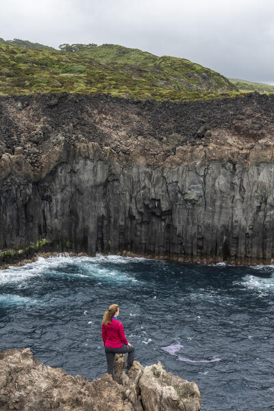 Young girl admires the cliffs of Terceria Island from the Miradouro de Alagoa, Terceria Island, Azores Islands, Portugal