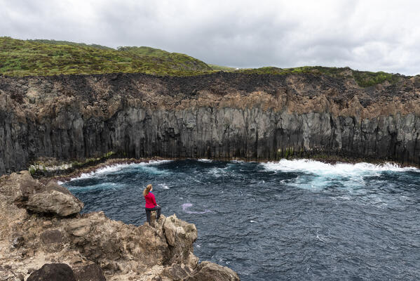 Young girl admires the cliffs of Terceria Island from the Miradouro de Alagoa, Terceria Island, Azores Islands, Portugal