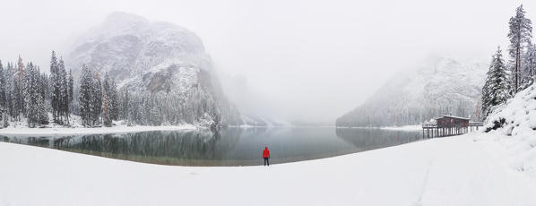 one person admires the splendid and famous Braies Lake undera a big snowfall, Natural Park Fanes-Sennes-braies, Dolomiti, municipality of Braies, Bolzano province, Trentino Alto Adige district, Italy, Europe.