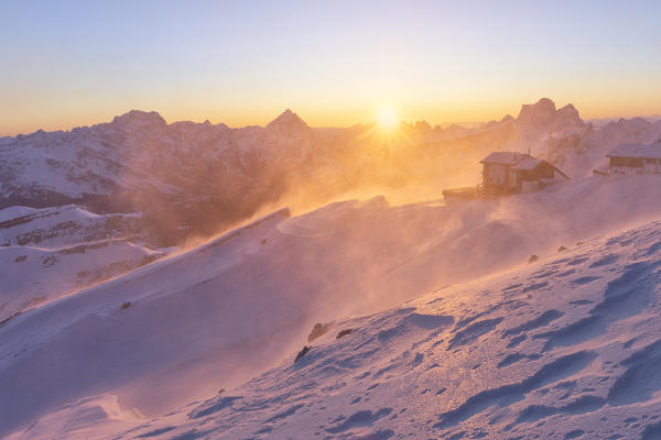 a windstorm lifts the snow in a cold winter sunrise at the Lagazuoi refuge, munipality of Cortina d'Ampezzo, Belluno province, Veneto District, Dolomiti, Italy, Europe