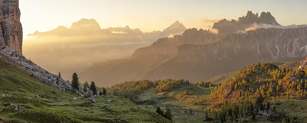 a warm light filters through the clouds and envelops the tops of the Cason di Formin mountains during a summer sunrise, Dolomites, municipality of Cortina d'Ampezzo, Belluno province, Veneto district, Italy, Europe