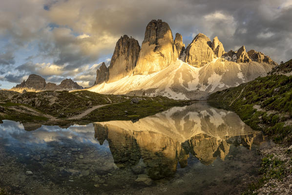 the majestic Tre Cime di Lavaredo are reflected in an alpine lake during a sunset with warm light, Dolomiti, Unesco World Heritage Site, belluno province, Veneto district, Italy, Europe