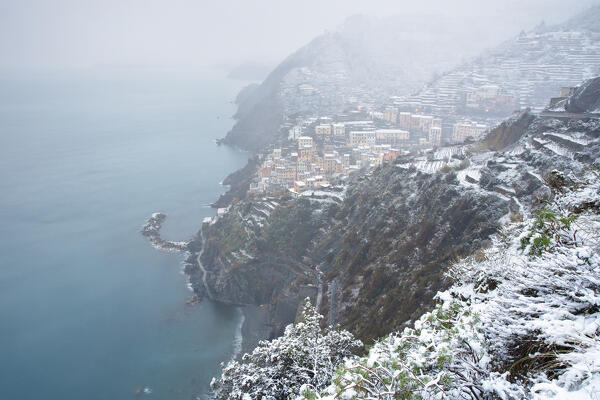 The snow envelops the cliffs of the Cinque Terre, near the town of Riomaggiore during a cold winter morning, National Park of Cinque Terre, UNESCO WORLD HERITAGE SITE, municipality of Riomaggiore, La Spezia province, Liguria district, Italy, Europe