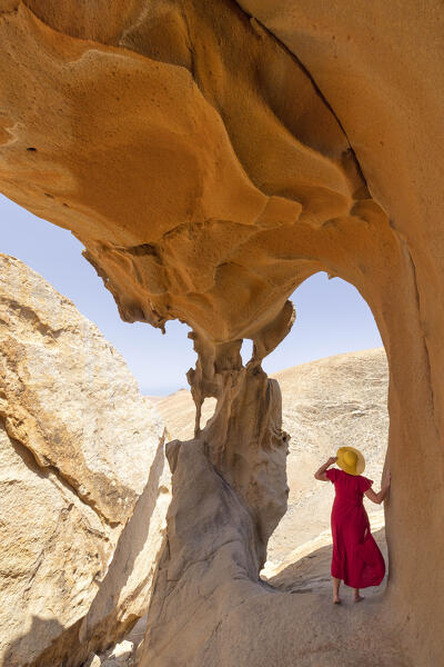 a tourist admires the view from the cave at Vega de Rio Palma during a sunny summer day, Fuerteventura, Canary Island, Spain, Europe