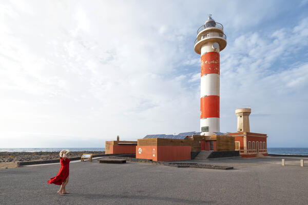 a tourist admires the Toston Lighthouse during a sunny summer day, Fuerteventura, Canary Island, Spain, Europe