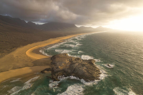 aerial view taken by drone of Cofete Beach during a summer warm sunset with El Isote peninsula in foreground, Natural Park de Jandia, Fuerteventura, Canary Island, Spain, Europe