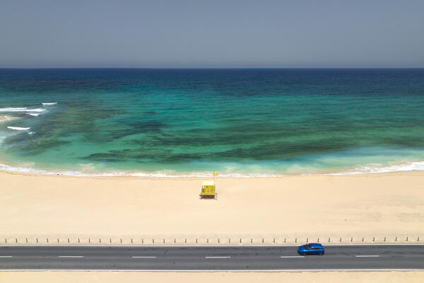 a blue car driving along the costal road near to Playa el Rosadero, during a sunny summer day, Natural Park of Corralejo, Fuerteventura, Canary Island, Spain, Europe