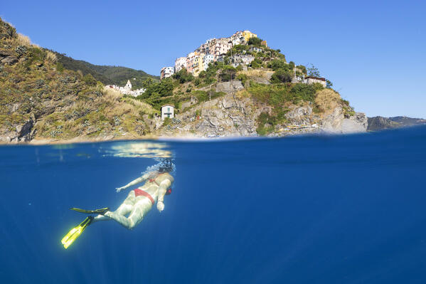 a girl snorkels in the sea of Corniglia during a splendid summer day, municipality of Vernazza, National Park of Cinque Terre, La Spezia province, Liguria, Italy, Europe