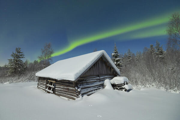 old cabin covered with snow in the arctic forest under the Northern Lights, Lapland, Finland