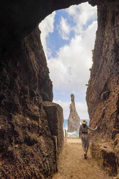 A girl enjoys the beautiful view from the basaltic cave towards the Praia da Ribeira da Janela beach during a spring day, Porto Moniz, Madeira Island, Portugal, Europe