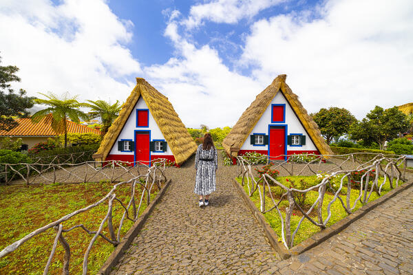 a girl admires the beautiful typical house's in Santana during a sunny spring day, Santana, Madeira, Portugal, Europe
