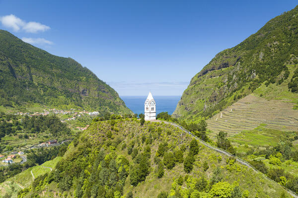 Capelinha de Nossa Senhora de Fatima clock tower on green hills surrounded by terraced fields, Sao Vicente, Madeira, Portugal
