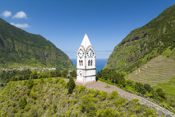 Capelinha de Nossa Senhora de Fatima clock tower on green hills surrounded by terraced fields, Sao Vicente, Madeira, Portugal