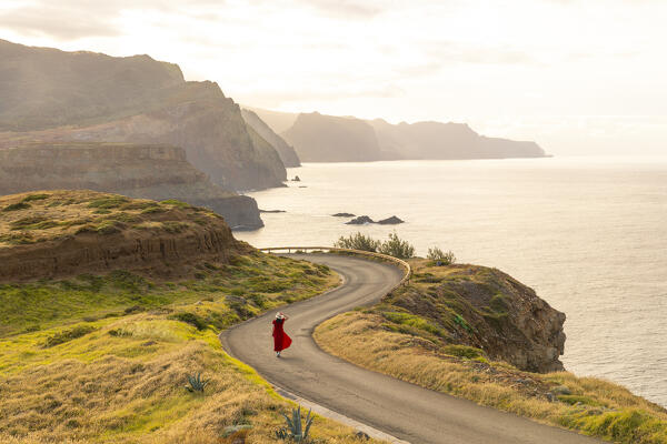 a girl enjoys the beautiful spring sunset along the asphalt road near to Miraoduro de Sao Lourenco, Madeira, Portugal, Europe (MR)