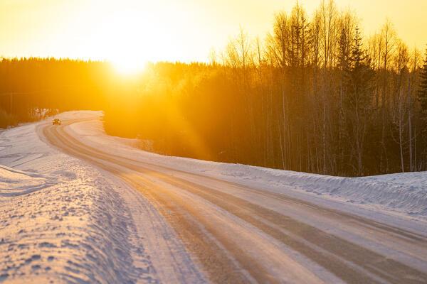 a snow-covered road along the Finnish Lapland forest during a winter blue hour, Finland, Europe
