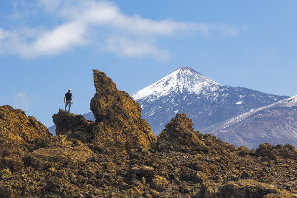 A boy enjoys the beautiful view from the lava field and admire the majestic Teide Volcano during a beautiful sunny day, Tenerife, Canary Islands, Spain, Europe