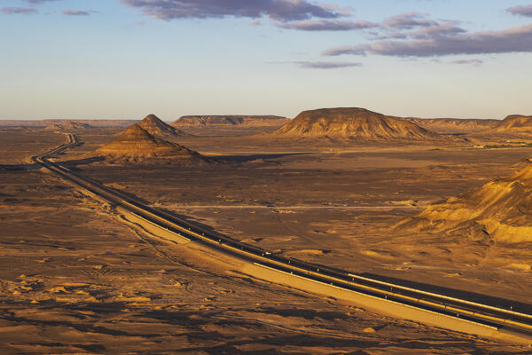 the scenic road that runs through the Black Desert illuminated by a warm sunlight, Egypt, Africa