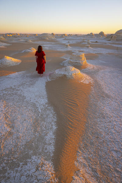 A woman walking close to the beautiful rocks formation in White Desert, during a beautiful sunrise, White Desert, Egypt, Africa