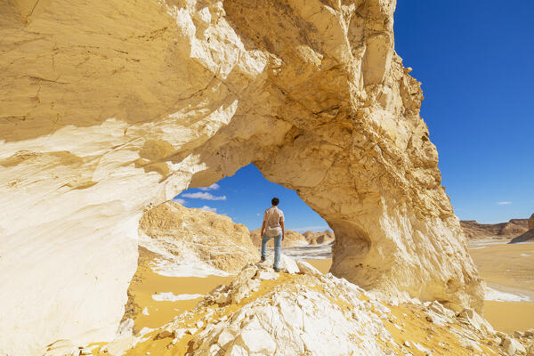 a boy admires the beautiful rock formations of the White Desert on a sunny day, White Desert, Egypt, Africa