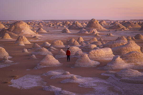 A woman walking close to the beautiful rocks formation in White Desert, during a beautiful sunrise, White Desert, Egypt, Africa