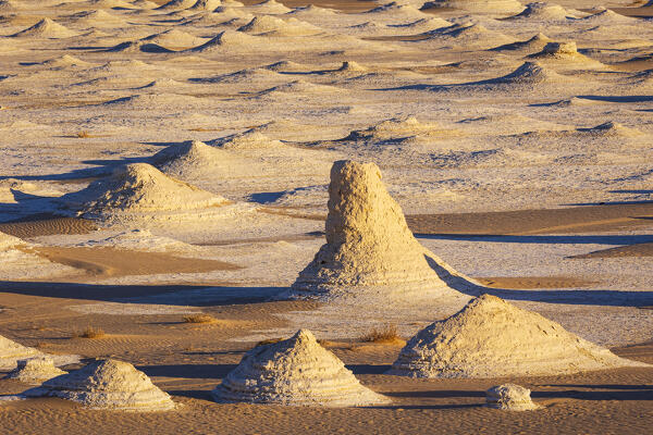 The first rays of the sun illuminate the spectacular rock formations of the incredible landscape of the White Desert, during a beautiful winter day, Egypt, Africa