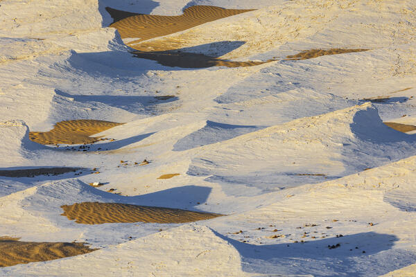 The first rays of the sun illuminate the spectacular rock formations and texture of the incredible landscape of the White Desert, during a beautiful winter day, Egypt, Africa