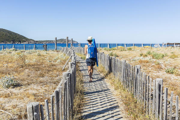 Tourist walks towards Chiuni beach (plage de Chiuni), Cargese, Corsica, France